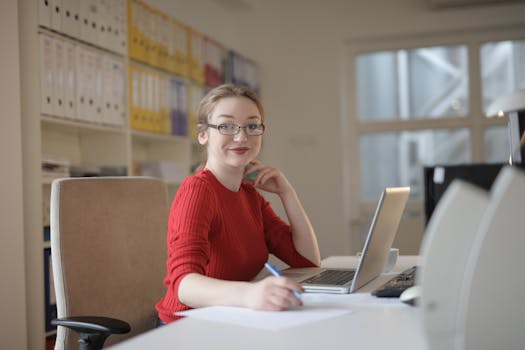 a person writing in a planner with a laptop and coffee on the table